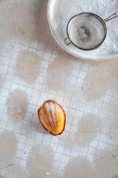 Top down view of a pattern of madeleine cakes in icing sugar, one cake central 写真素材