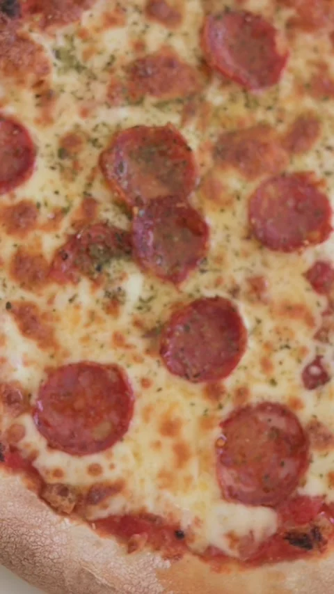 Top-down view of pepperoni pizza with golden cheese and thick crust Stock Footage 318578806