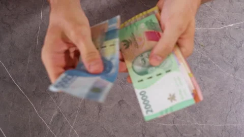 Top Down View of Person Comparing Indonesian Rupiah and Thai Baht Banknotes by H Stock Footage 339207242