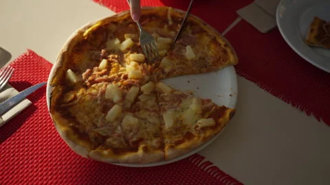 Top-down view of person cutting slice of freshly baked hawaiian pizza with .. Stock Footage 321021341
