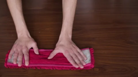 Top-down view of a person's hands meticulously cleaning a dark wooden floor Stock Footage 327158107