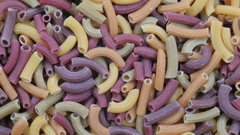 Top down view. A pile of organic, vegetable-flavored, multicolored tube pasta Stock Footage 296567345