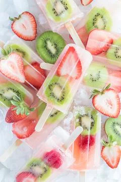Top down view of a pile of refreshing strawberry kiwi popsicles on ice. Stock Photos