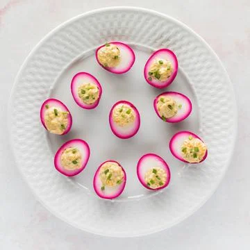 Top down view of a plate filled with beet juice soaked devilled eggs for Easter. Stock Photos