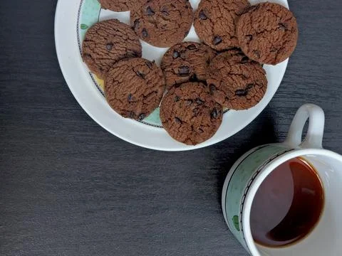 A top-down view of a plate filled with chocolate chip cookies on a dark woo.. Stock Photos