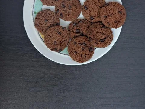 A top-down view of a plate filled with chocolate chip cookies on a dark woo.. Stock Photos