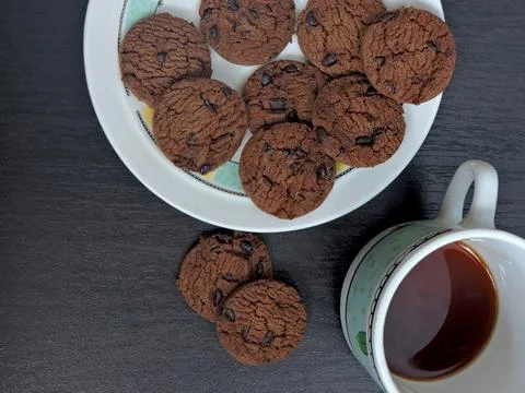 A top-down view of a plate filled with chocolate chip cookies on a dark woo.. Stock Photos