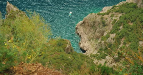Top down view of pleasure boat floating below steep cliffs in summer Capri Italy Video stock 317241219