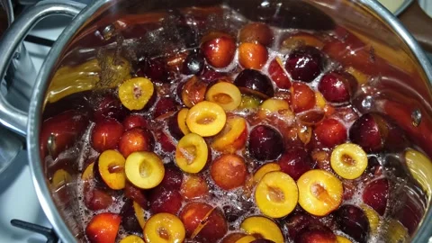 Top-down view of plums cooking in a bubbling syrup, making fruit jam or Stock Footage 340263171