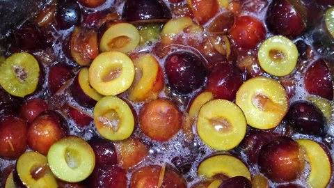 Top-down view of plums cooking in a bubbling syrup, making fruit jam or Stock Footage 340263181