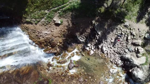 Top down view of powerful waterfall and hikers with dutch tilt effect 스톡 동영상 334625043
