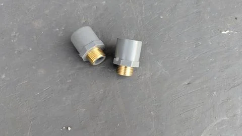 A top down view presents two grey PVC pipe adapter fittings with golden bra.. Stock Photos