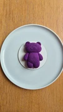 Top-down view of a purple teddy bear-shaped dessert placed on a white plate on a 스톡 사진