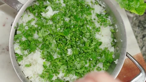 Top-down view of rice garnished with fresh green herbs in a kitchen Stock Footage 296740476