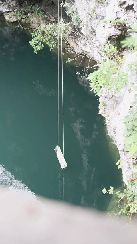 Top down view of a rope swing swaying gently over the turquoise water Vídeo Stock 340639190