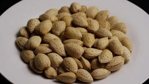 Top down view of rotating almonds on white plate Stock Footage 327911166