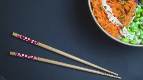 Top Down View of rotating Poke Bowl and chopsticks on Black Background Stock Footage 306651879