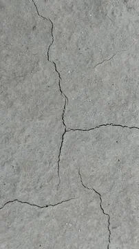Top down view of a rough, weathered gray concrete surface with prominent dark Stock Photos