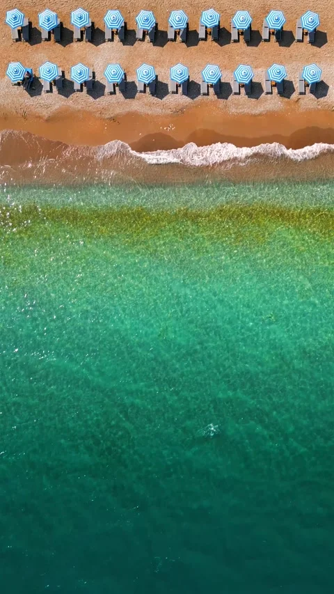 Top-down view of sandy beach with sun umbrellas and turquoise sea water Stock Footage 301541880