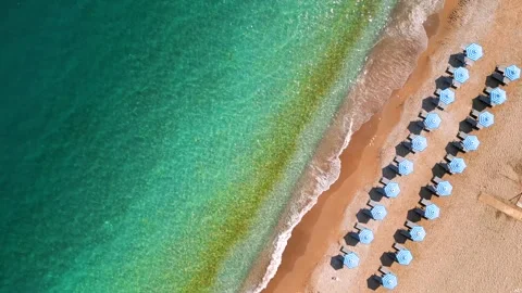Top-down view of sandy beach with sun umbrellas and turquoise sea water Stock Footage 302843727
