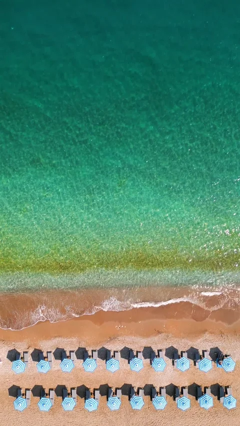 Top-down view of sandy beach with sun umbrellas and turquoise sea water Stock Footage 318485028
