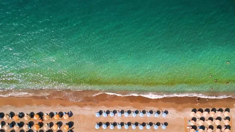 Top-down view of sandy beach with sun umbrellas and turquoise sea water Stock Footage 321948280