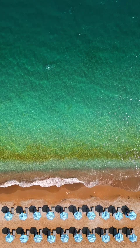 Top-down view of sandy beach with sun umbrellas and turquoise sea water Video stock 342834002