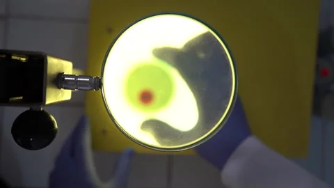 Top-Down View of Scientist Examining Fluorescent Liquid Under Magnifying Light Vídeos de archivo 334941605