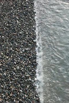 Top Down View of Sea Water at the Edge of a Pebble Beach Shore Stock Photos