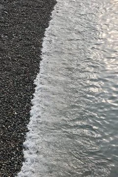 Top Down View of Sea Water at the Edge of a Pebble Beach Shore Stock Photos