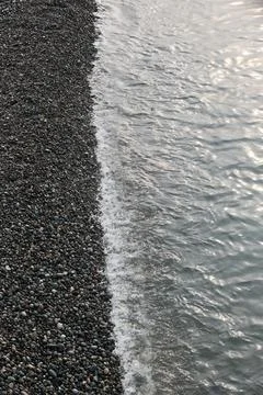 Top Down View of Sea Water at the Edge of a Pebble Beach Shore Stock Photos