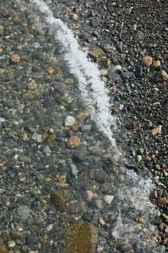 Top Down View of Sea Water at the Edge of a Pebble Beach Shore Stock Photos