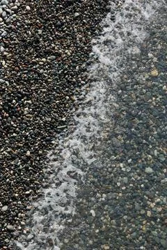 Top Down View of Sea Water at the Edge of a Pebble Beach Shore Stock Photos