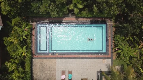 Top down view serene scene woman enjoying swim in private pool deep within .. Vídeo Stock 309395551