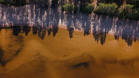 Top-down view of a shallow sandy shoreline with soft ripples and subtle dark Video stock 327396266