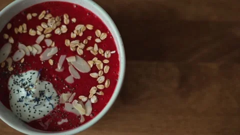 A top-down view shows a bowl of raspberry yogurt topped with almonds, poppy Stock Footage 339094252