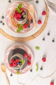A top down view shows glass jars of overnight oats with chia seeds topped w.. Stock Photos