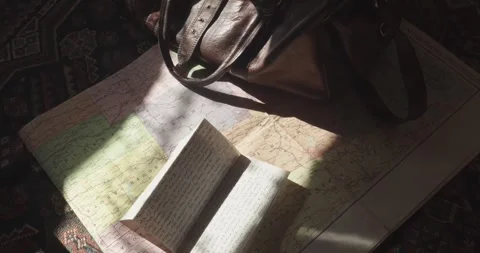 Top-down view shows a leather holdall on a USA road map beside a handwritten Stock Footage 344348092