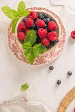 A top-down view shows a rustic bowl filled with fresh raspberries and blueb.. Stock Photos