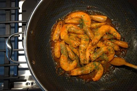 Top down view of shrimp with green herbs inside wok Stock Photos