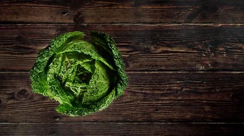 Top down view, single raw savoy kale cabbage on dark wooden board, wide banne Stock Photos