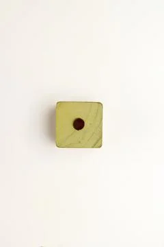 Top-down view of a single yellow-green square wooden bead with a central ho.. Stock Photos