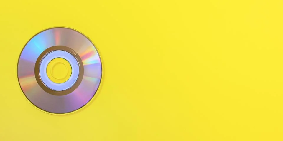 Top down view, small CD shiny / rainbow side, on yellow board, space for text Stock Photos