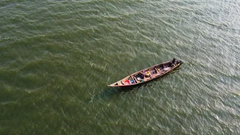 Top-down view of a small fishing boat afloat on shimmering green ocean water Stock Footage 314472454