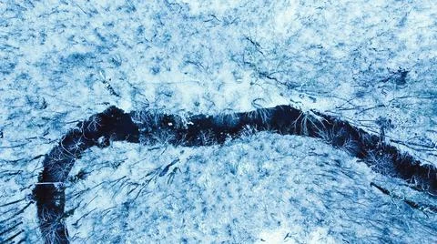 Top down view of small river in snow covered winter forest, drone view Stock Photos