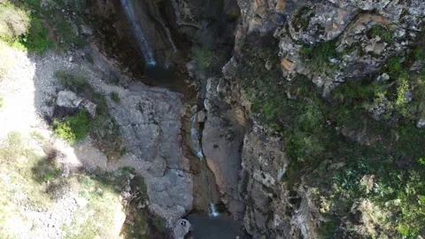 Top down view of small waterfall cascading into rocky pond in mountain gorge Видео 334625126