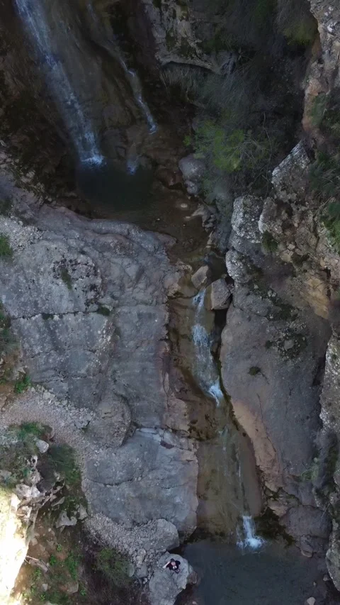 Top down view of small waterfall cascading into rocky pond in deep gorge Stock Footage 336691786
