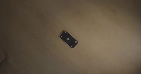 Top-down view of a smartphone with tracking markers on a wooden floor. Vídeo Stock 330239920