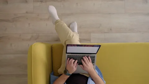 Top down view of sofa on which man sits down with laptop and work Stock Footage 243639624