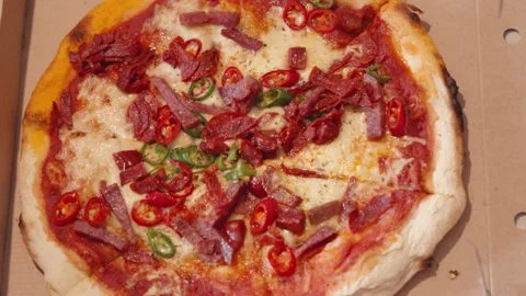Top Down View of Spicy Meat Pizza with Pepperoni, Salami, Chillies in Cardboard Stock Footage 340855349